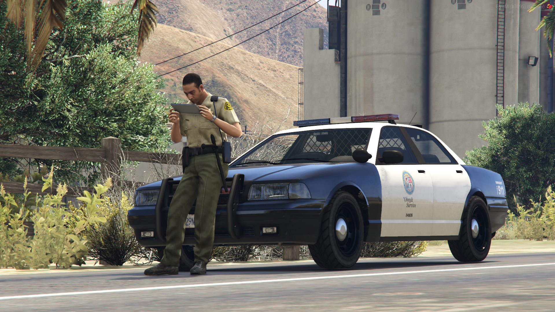 Police officer using a handheld ANPR terminal beside a patrol car